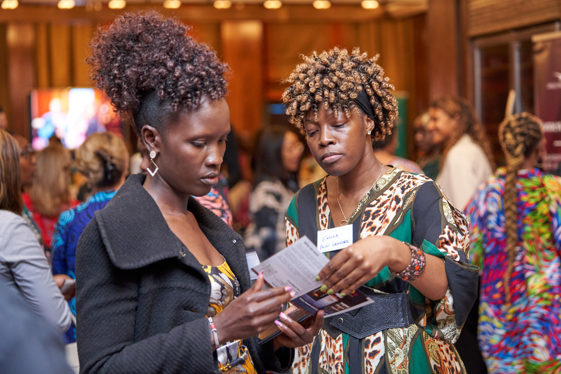 Two delegates connecting and reviewing programme details at a Women Creating Wealth business exchange